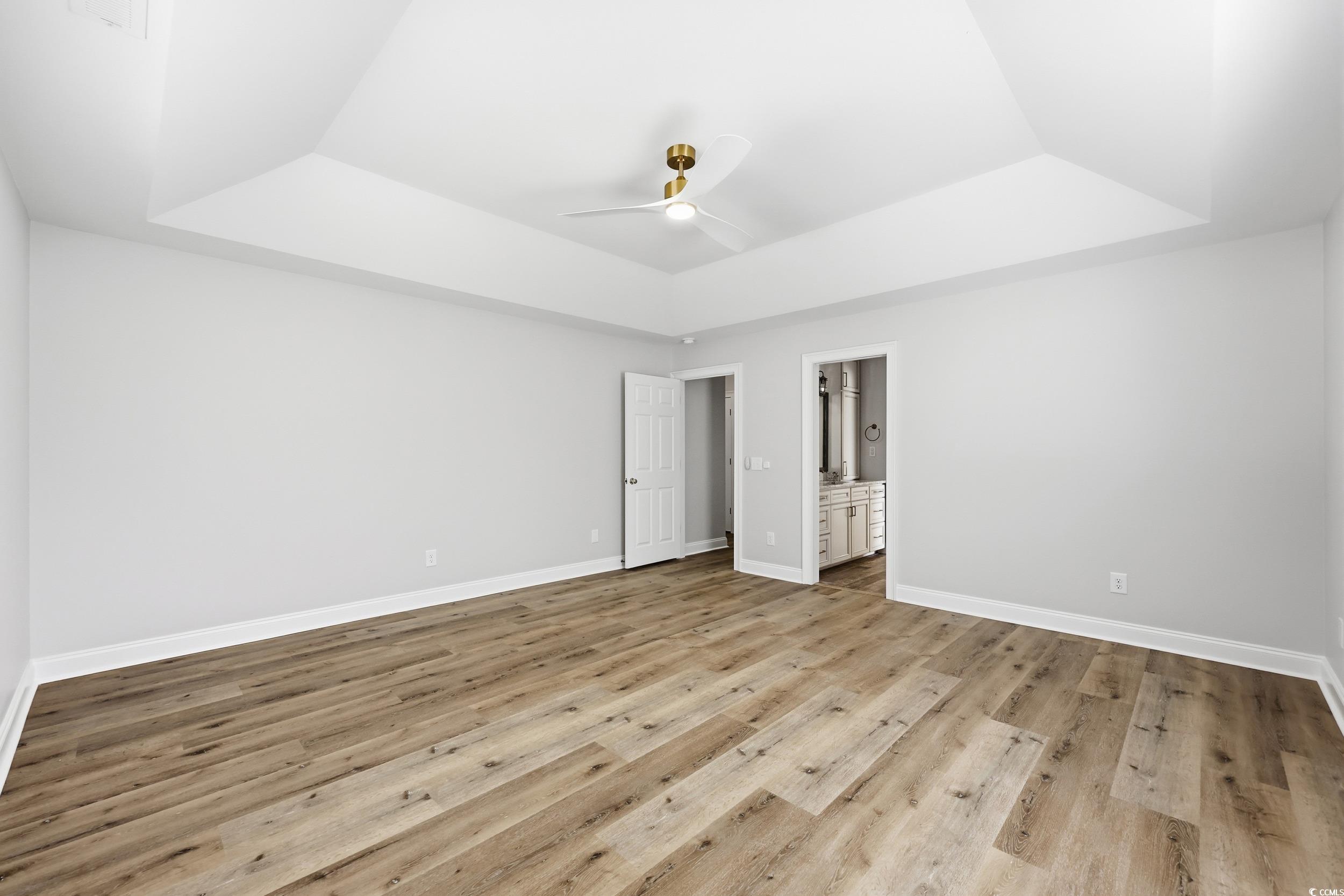 4337 State Highway 65 Conway, SC 29526 - Photo 17 of 39 Unfurnished bedroom with a tray ceiling, ceiling fan, light wood-style flooring, and ensuite bathroom