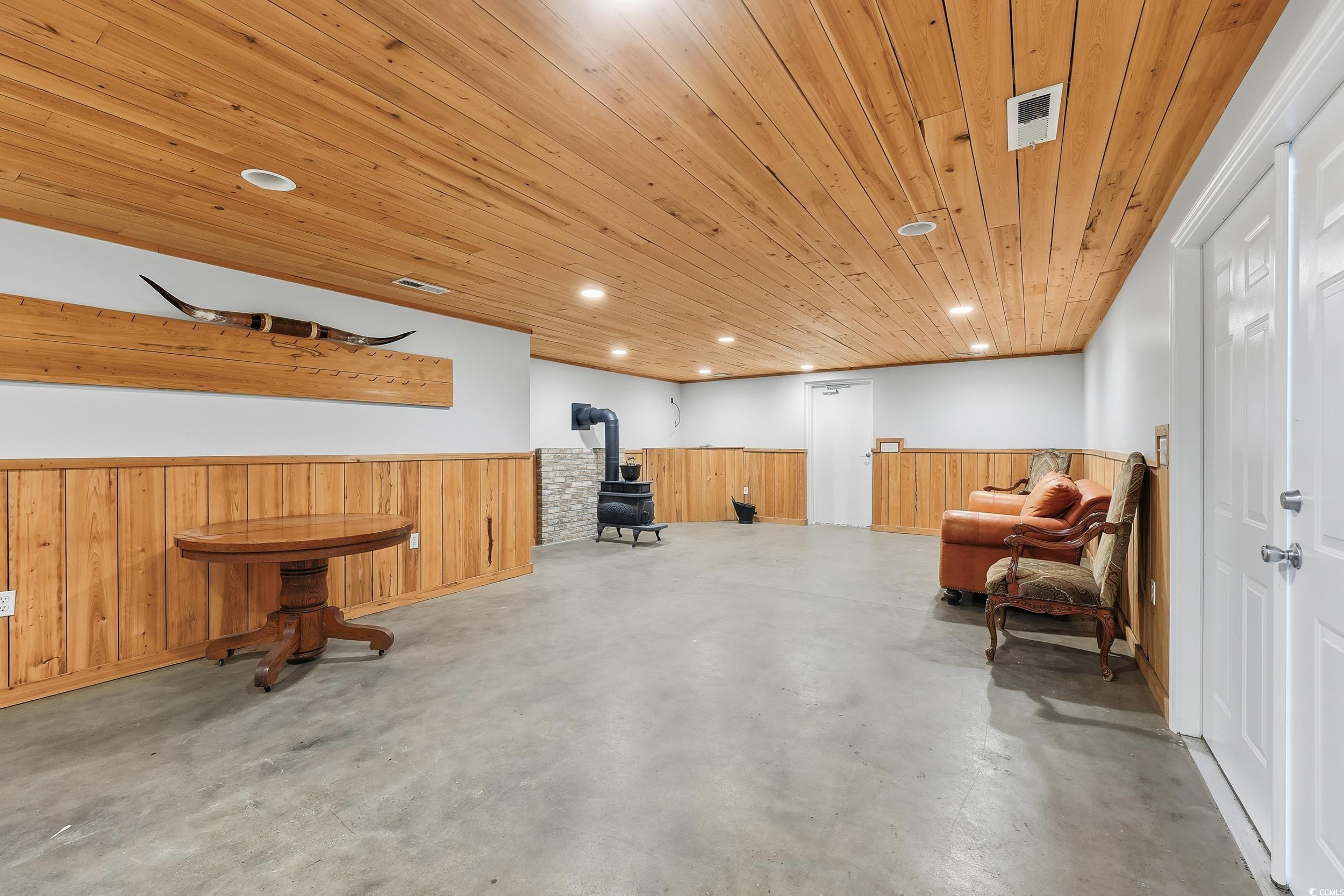 4337 State Highway 65 Conway, SC 29526 - Photo 28 of 39 Sitting room featuring wainscoting, wood walls, a wood stove, recessed lighting, and concrete floors