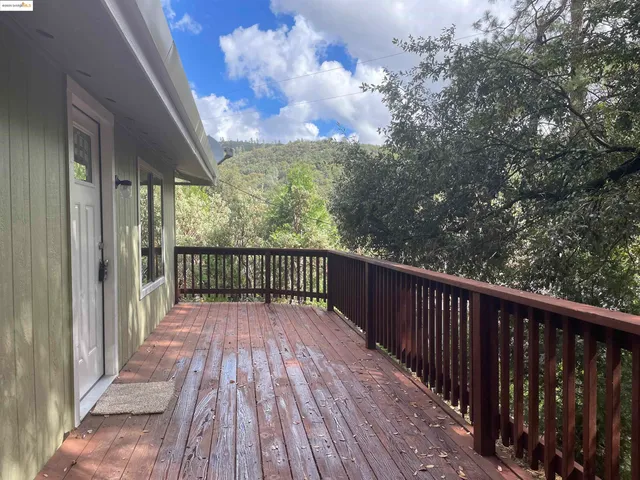 a balcony with wooden floor and trees in the back