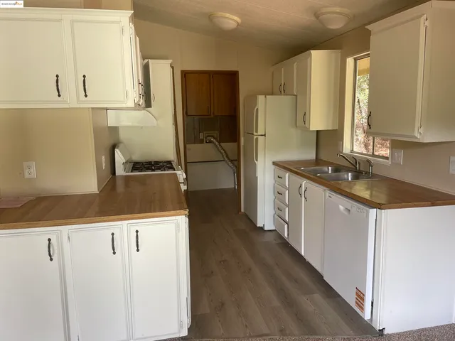 a kitchen with granite countertop a sink a stove and refrigerator