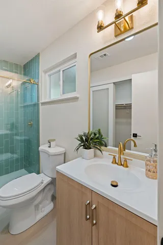 a bathroom with a sink a toilet a mirror and shower