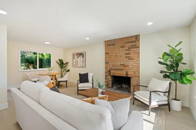 a living room with furniture fireplace and a large window