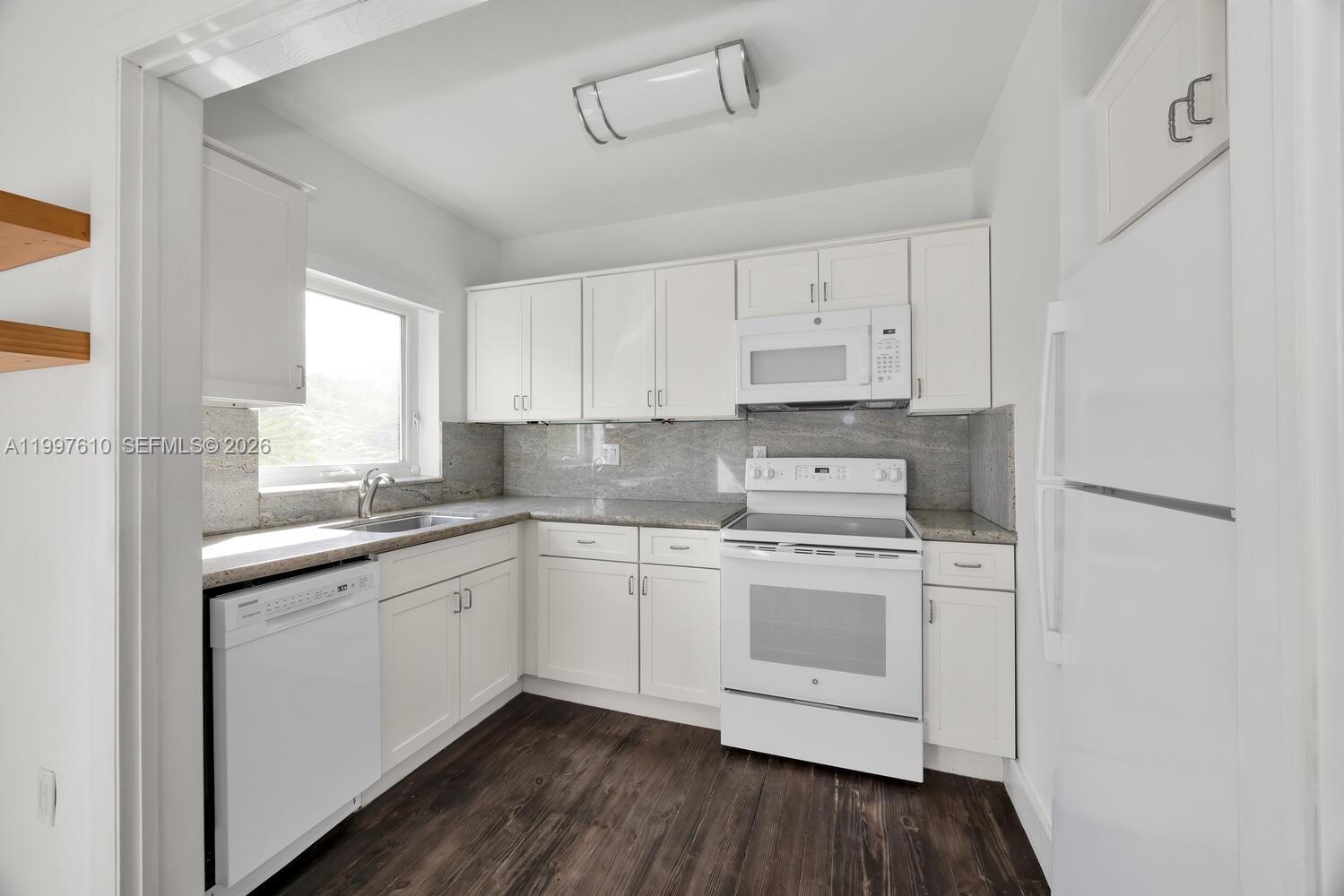 5510 Southwest 76th Street, Unit C Miami, FL 33143 - Photo 5 of 14 a kitchen with stainless steel appliances granite countertop white cabinets sink and stove