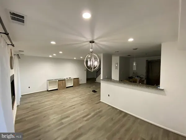 an empty room with wooden floor a ceiling fan a fireplace and windows