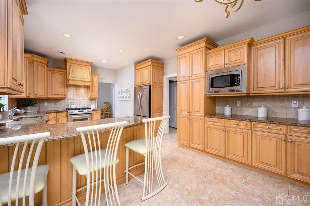 133 Thomas Drive Clark, NJ 07066 - Photo 14 of 30 a kitchen with stainless steel appliances granite countertop a stove top oven a sink a dining table and chairs