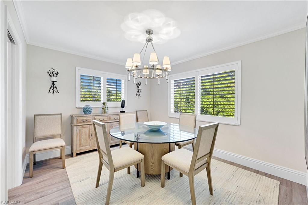 4180 Crayton Road, Unit E8 Naples, FL 34103 - Photo 3 of 20 a dining room with furniture a chandelier and wooden floor