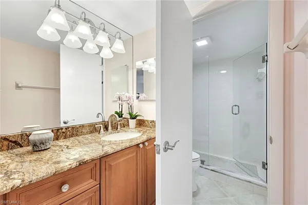 a bathroom with a granite countertop sink a mirror and a shower