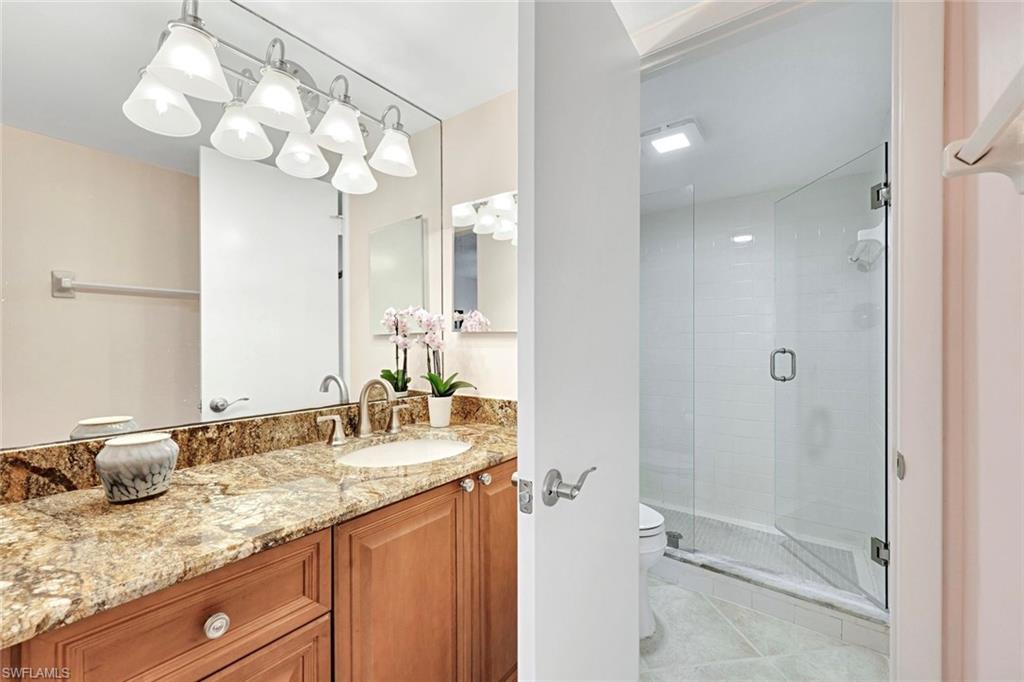 4180 Crayton Road, Unit E8 Naples, FL 34103 - Photo 8 of 20 a bathroom with a granite countertop sink a mirror and a shower