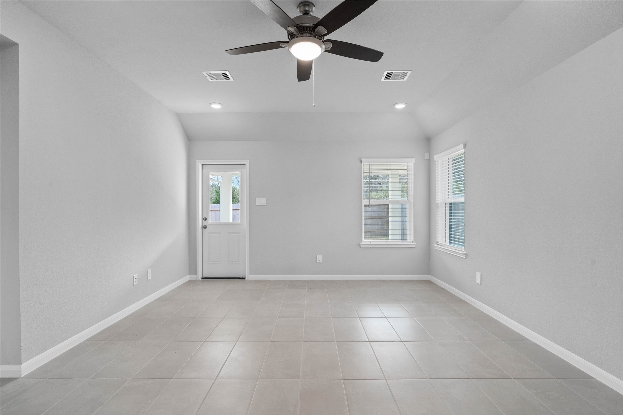 19555 Montgomery Rdg Way Montgomery, TX 77316 - Photo 23 of 38 A bright and airy open-concept space featuring tile flooring, sloped ceilings with recessed lighting and ceiling fan, abundant natural light from large windows (fitted with blinds), and an access door to the back covered patio.