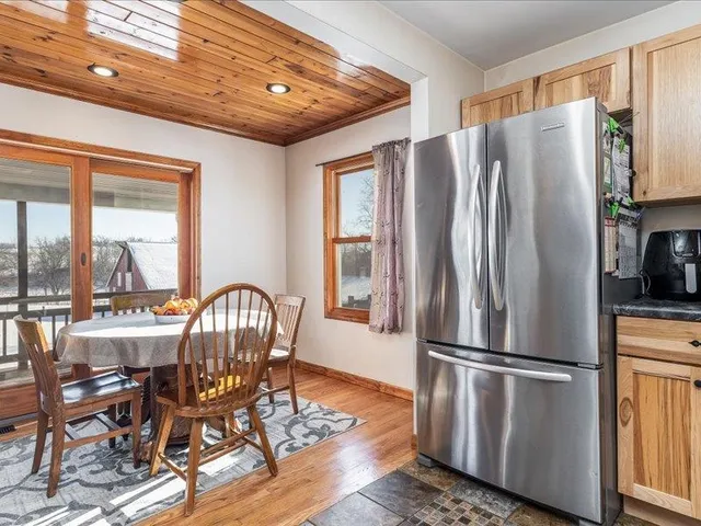 a kitchen with stainless steel appliances granite countertop a refrigerator a stove a dining table and chairs with wooden floor