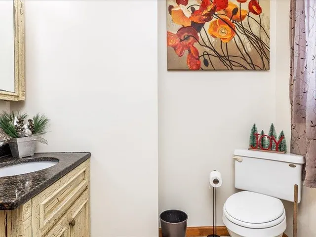 a bathroom with a granite countertop toilet and a sink