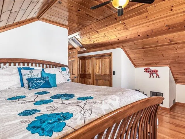 a bedroom with a bed and a dresser with wooden floor