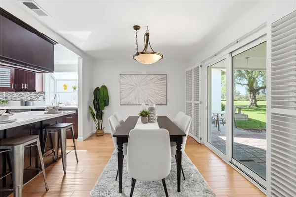 a dining room with wooden floor a chandelier a wooden table and chairs