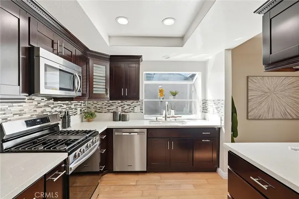 a kitchen with stainless steel appliances granite countertop a stove a sink dishwasher and a microwave oven with wooden cabinets