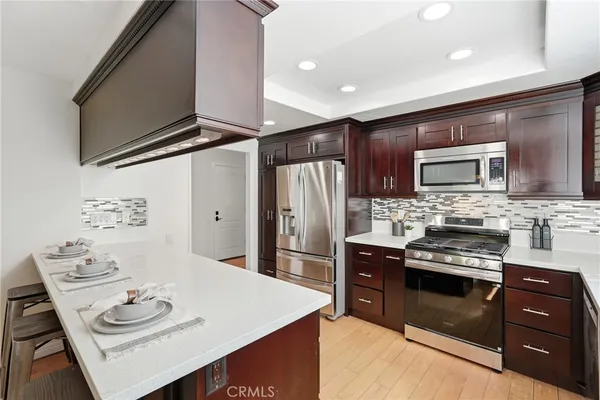 a kitchen with stainless steel appliances granite countertop a sink dishwasher stove and refrigerator with wooden floor