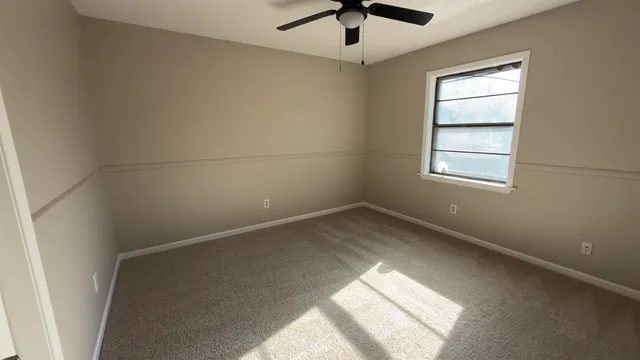 an empty room with a window and a fan
