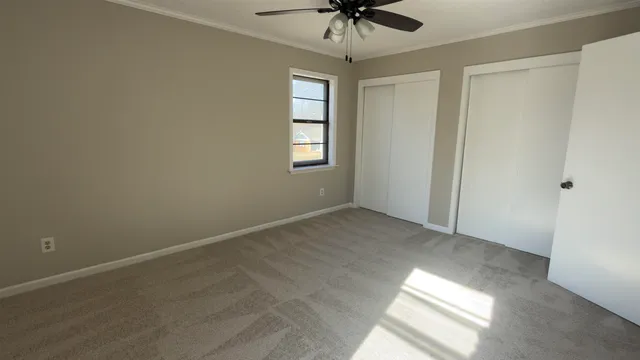an empty room with a chandelier fan and windows