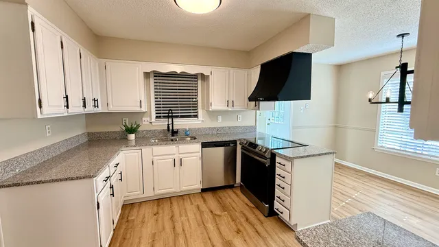 a kitchen with granite countertop a sink a stove and cabinets