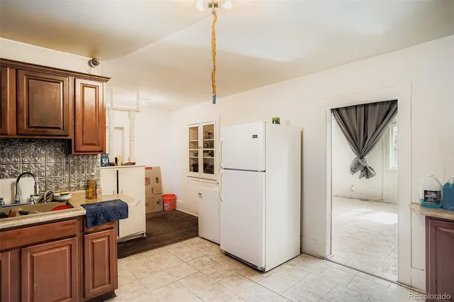 a kitchen with stainless steel appliances kitchen island granite countertop a refrigerator a sink a stove and white cabinets with wooden floor