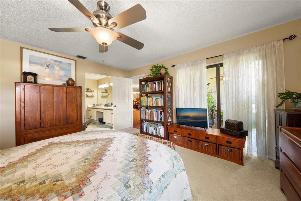 1801 East Lake Road South, Unit 10D Palm Harbor, FL 34685 - Photo 13 of 27 a bedroom with furniture and a flat screen tv