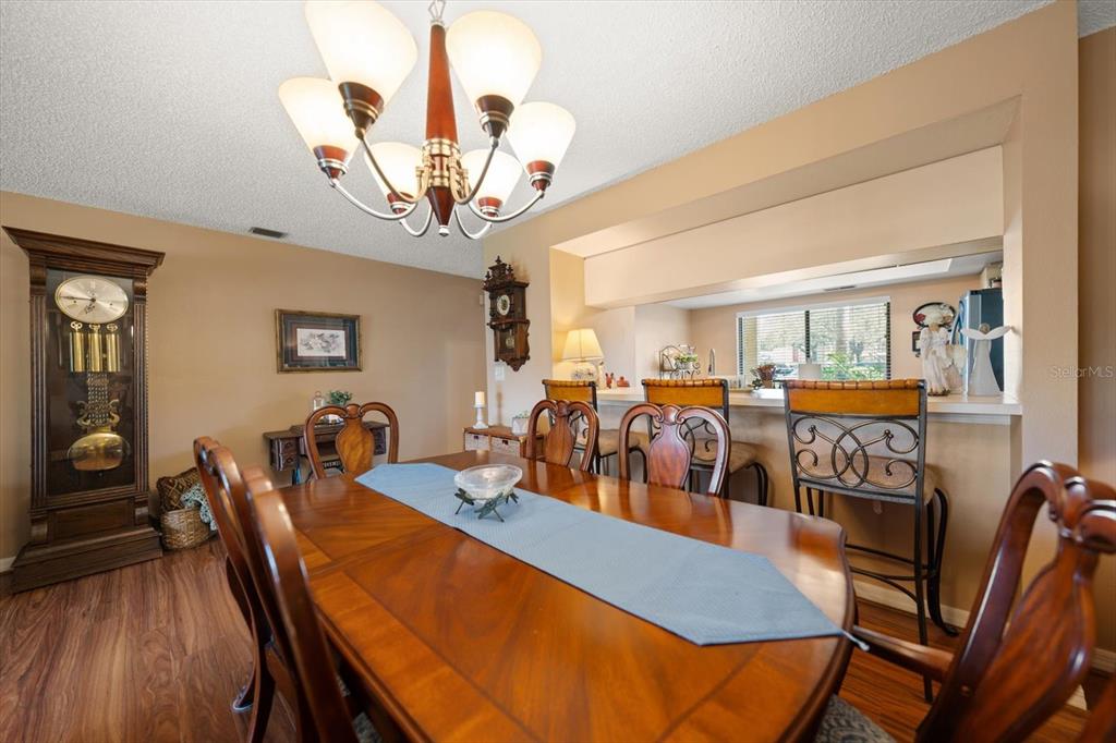 1801 East Lake Road South, Unit 10D Palm Harbor, FL 34685 - Photo 7 of 27 a view of a dining room with furniture wooden floor and chandelier