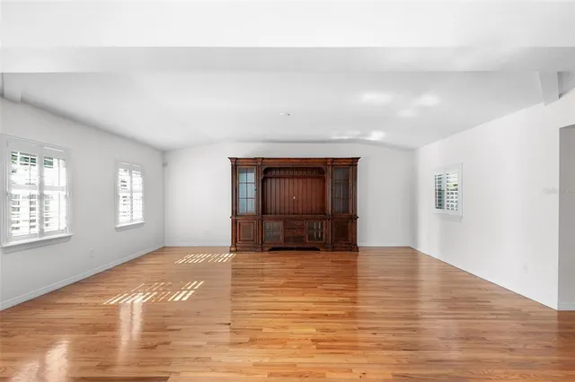 a view of empty room with wooden floor and window