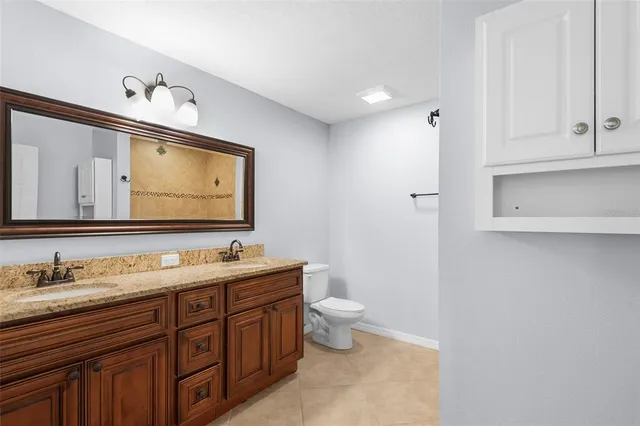 a bathroom with a granite countertop bathtub shower sink mirror and toilet