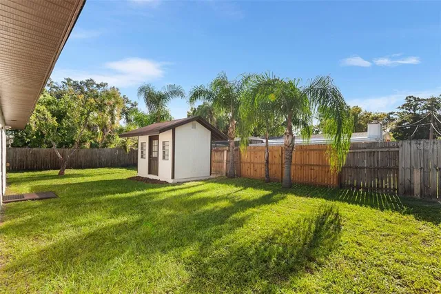 a view of a house with a yard and a large tree