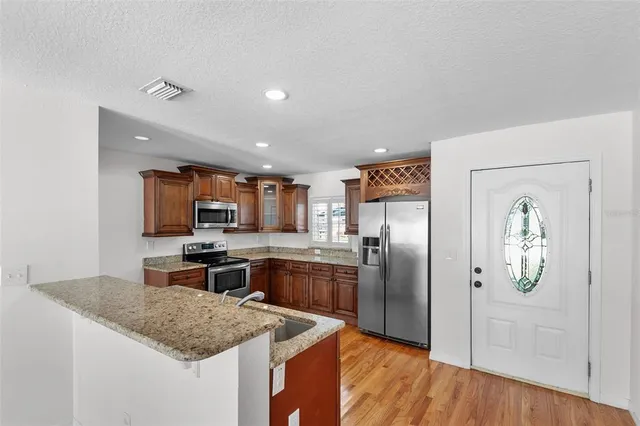 a large kitchen with stainless steel appliances granite countertop a sink stove and refrigerator