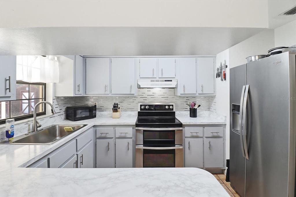 6940 Southeast 52nd Street Ocala, FL 34472 - Photo 12 of 45 a kitchen with granite countertop a sink stove and refrigerator