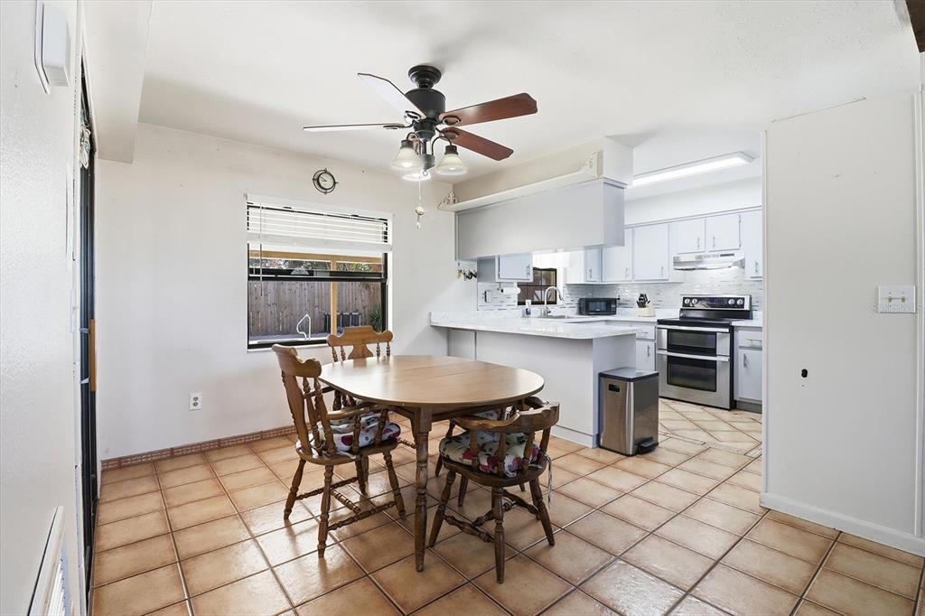 6940 Southeast 52nd Street Ocala, FL 34472 - Photo 9 of 45 a kitchen with stainless steel appliances a dining table chairs and white cabinets