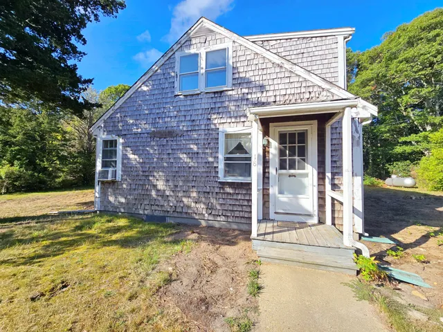 a view of a house with a small yard and a large tree