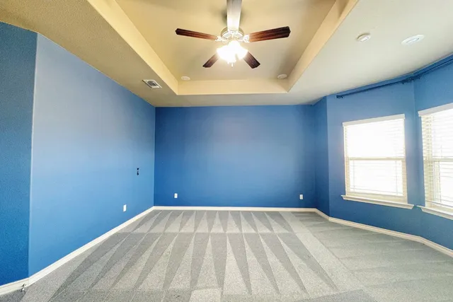 an empty room with windows and fan