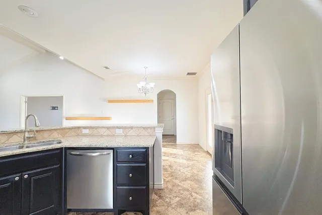a kitchen with a granite countertop sink and refrigerator