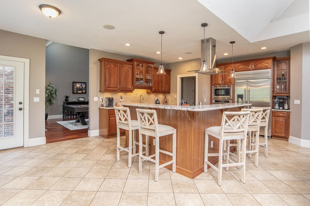 19 Round Farm Road Rehoboth, MA 02769 - Photo 13 of 42 a kitchen with stainless steel appliances kitchen island granite countertop a dining table chairs and white cabinets