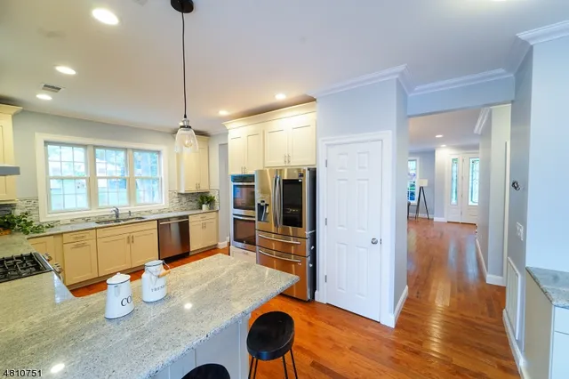 a kitchen with stainless steel appliances granite countertop a refrigerator and wooden floor