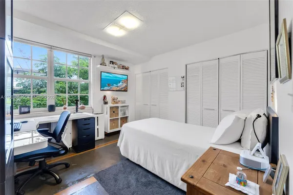 a bedroom with a bed workspace and a window