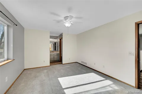 an empty room with chandelier fan and windows