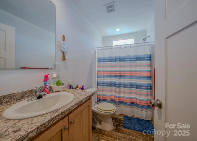 a bathroom with a granite countertop sink vanity mirror and toilet