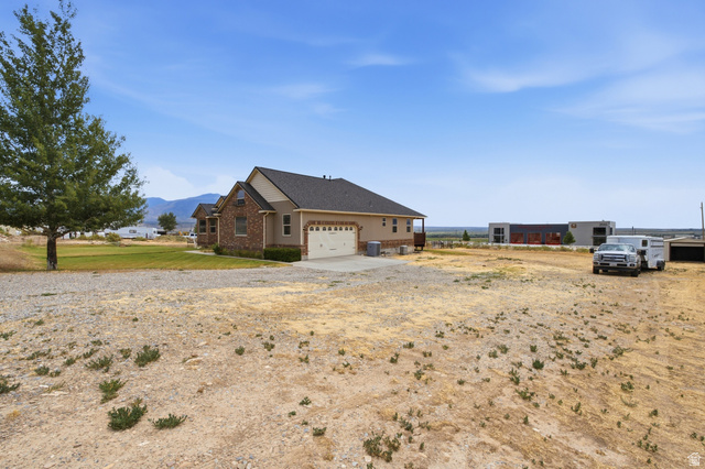2567 West Rim Rock Drive Stockton, UT 84071 - Photo 5 of 64 Exterior featuring brick and stucco siding, a multi-pane garage door, and a dark shingle roof