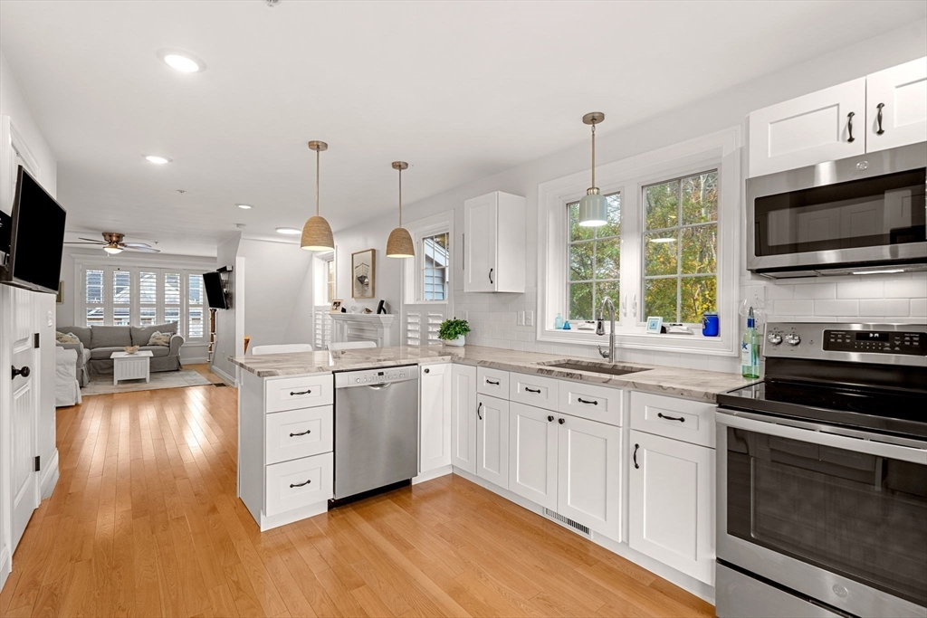 45 Old County Road, Unit 1 Salisbury, MA 01952 - Photo 9 of 40 a kitchen with stainless steel appliances kitchen island granite countertop a stove top oven a sink dishwasher a dining table and chairs with wooden floor