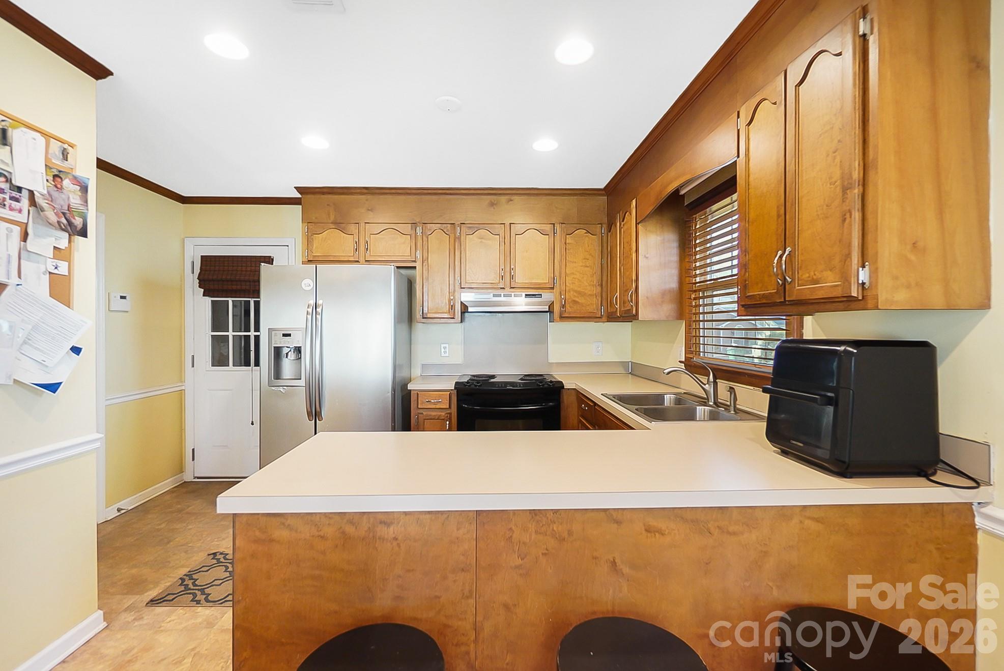 6906 Streamside Drive Charlotte, NC 28212 - Photo 13 of 48 a kitchen with stainless steel appliances a refrigerator a sink a stove top oven a counter space and a window