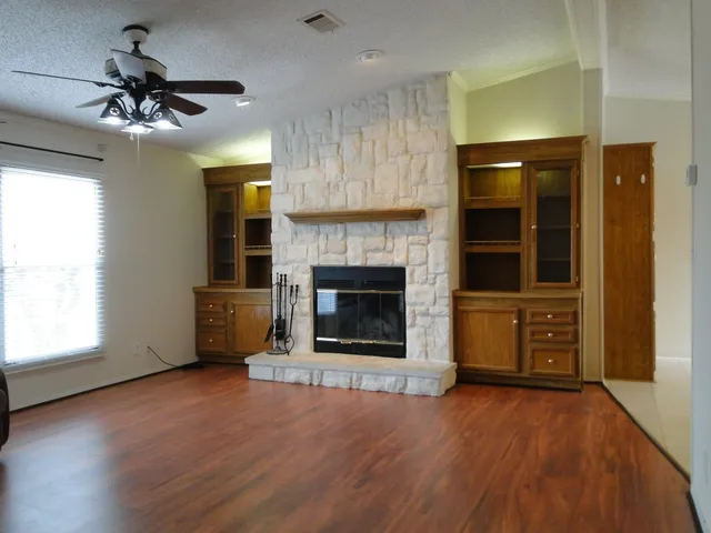 a view of an empty room with a fireplace and a window