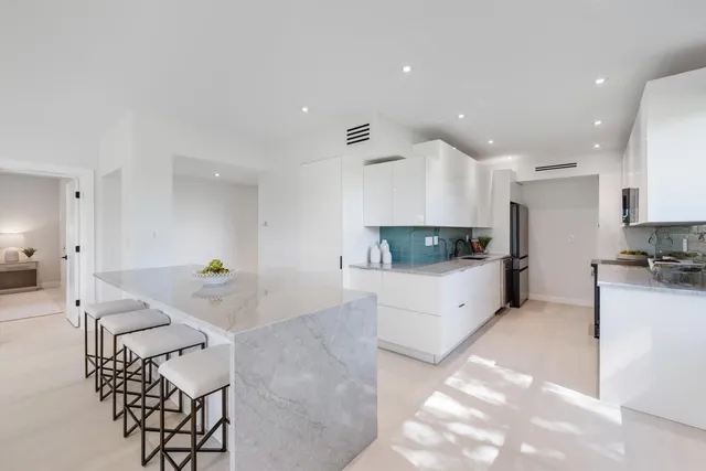 a large white kitchen with stainless steel appliances kitchen island granite countertop a sink and cabinets