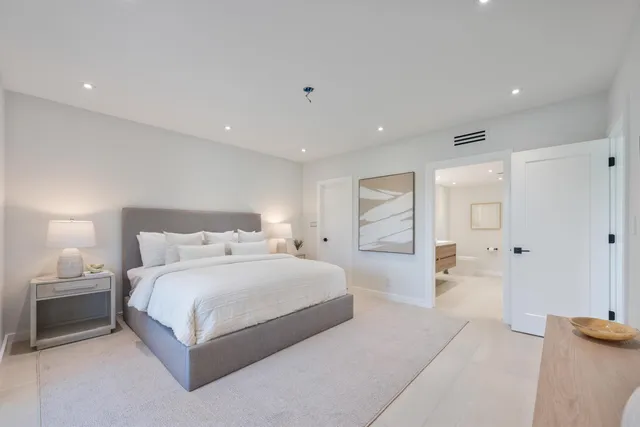 a spacious bedroom with a bed and a lamp