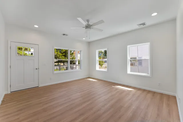 an empty room with wooden floor and windows