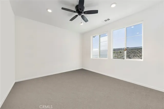 an empty room with a window and a ceiling fan