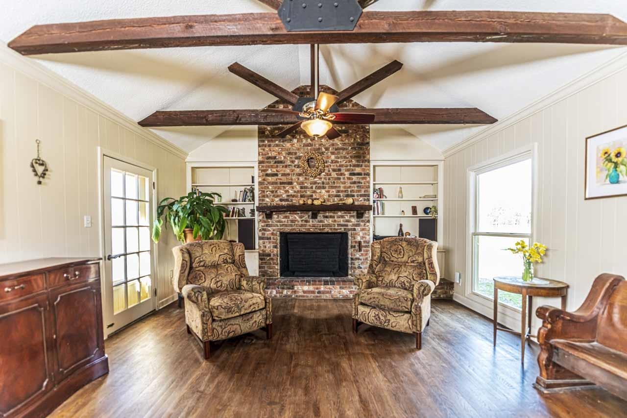 6746 Old Millington Road Millington, TN 38053 - Photo 16 of 40 Living room featuring beamed ceiling, a brick fireplace, dark wood-type flooring, wood walls, and built in features