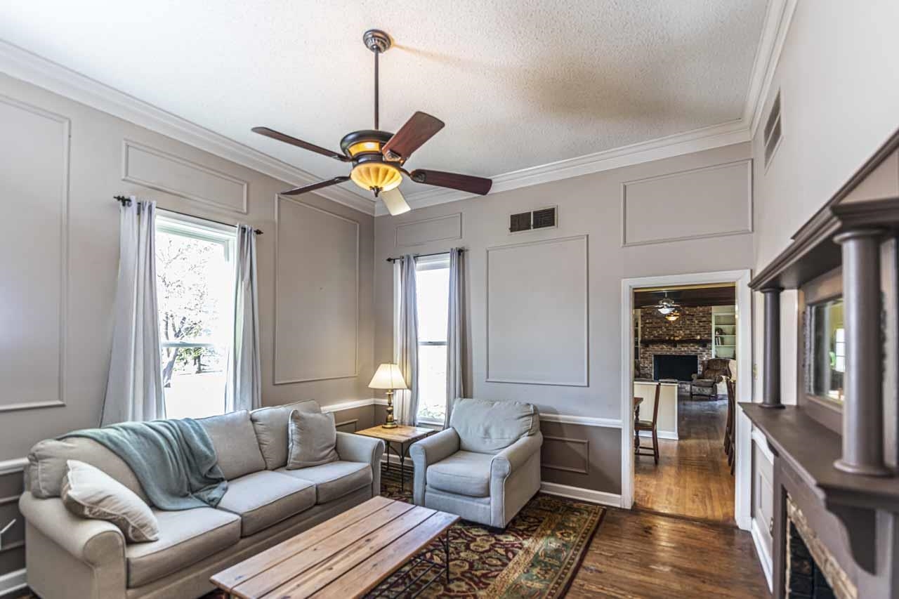 6746 Old Millington Road Millington, TN 38053 - Photo 8 of 40 Living area with ceiling fan, a decorative wall, dark wood-style flooring, a fireplace, and ornamental molding