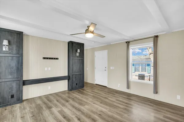 a view of empty room with wooden floor and fan